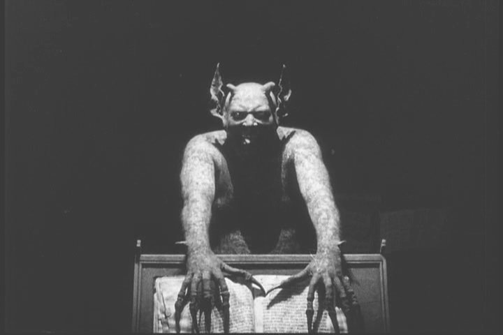 Devil leaning over a podium to grab a book